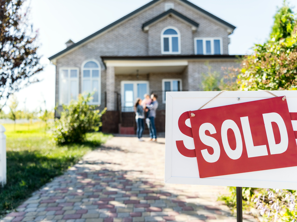 sold sign house and family in background
